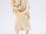 une figurine ancienne en ivoire représentant une femme tenant un panier de fleurs