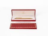une boîte rouge contenant un stylo, posée sur une surface blanche