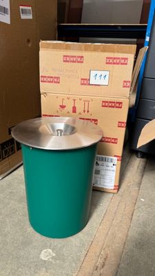 a green trash can sitting on the floor next to a cardboard box