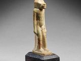 an egyptian statue of a man standing on a wooden base