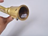 a hand holding a brass pipe with a sticker on it