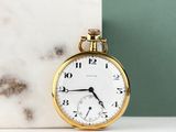 a gold pocket watch sitting next to a marble block