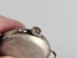 a person holding a silver pocket watch in their hand