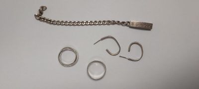 un bracelet en argent, une bague et une chaîne posés sur une table
