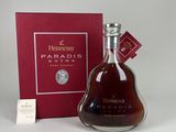 une bouteille de cognac Hennessy devant une boîte rouge