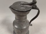 an old silver coffee pot sitting on top of a white table