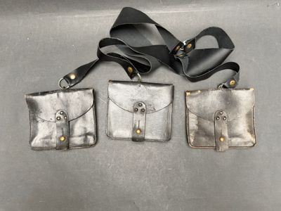 trois pièces en cuir argenté, ornées de boutons dorés et d'un ruban noir