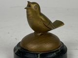 statue d'un oiseau posée sur un socle en marbre, sur fond blanc