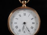 a gold pocket watch with roman numerals on the face