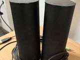 two black speakers sitting on top of a wooden table next to a laptop