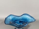 une image représentant un bol en verre bleu posé sur une table