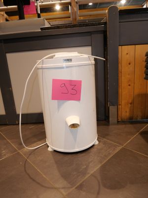 a white trash can sitting on the floor with a pink sticker on it