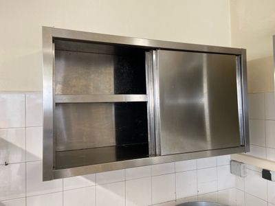 un lavabo en acier inoxydable dans une salle de bains, surmonté d'un miroir