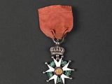 a close up of a medal on a black surface with a red ribbon