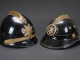 deux casques noirs ornés de galons dorés sur fond gris