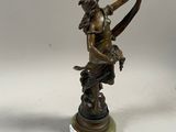 an antique bronze statue of a woman with a bow