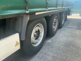 a green semi truck with a flat bed parked in a parking lot