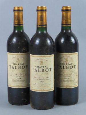 three bottles of red wine are lined up on a gray surface
