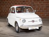 a small white car that is parked in front of a brick wall
