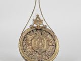 a gold plate with a bird on it hanging from a rope