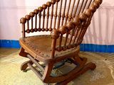 un fauteuil à bascule en bois dans une pièce aux murs roses