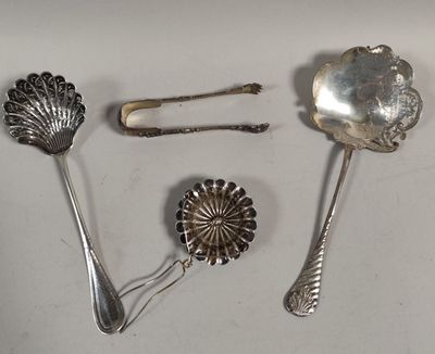 trois cuillères en argent et un repose-cuillère posés sur une surface blanche