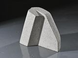 concrete sculpture of a triangular shape on a reflective surface