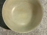 a white bowl sitting on a table with a shadow on it