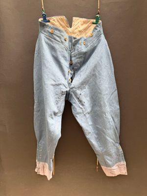an old pair of jeans hanging on a clothes line on a brown wall