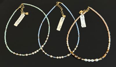trois colliers composés de perles dorées et bleues sur fond noir