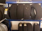 tires stacked on a blue cart in a garage with other tires in the background