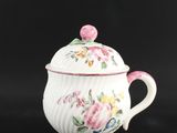 une image représentant une théière blanche ornée de fleurs roses