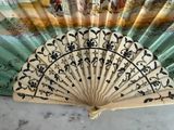 a fan that is sitting on a table with a painting on it