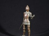 une figurine antique en bronze représentant un chevalier tenant une épée