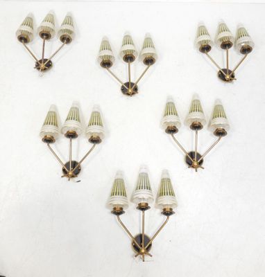 six white and gold wall sconces mounted on a white wall