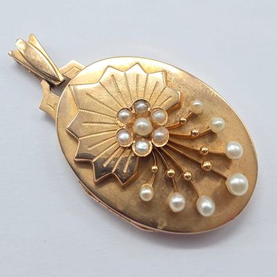 a gold locke with pearls on it on a white surface