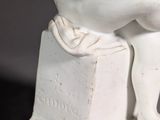 a white statue of a man sitting on a box
