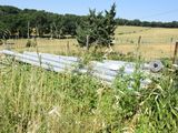a fence in the middle of a field with a bunch of trees in the background