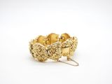 a close up of a gold bracelet on a white surface