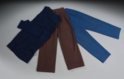 trois paires de pantalons posées les unes sur les autres sur une table