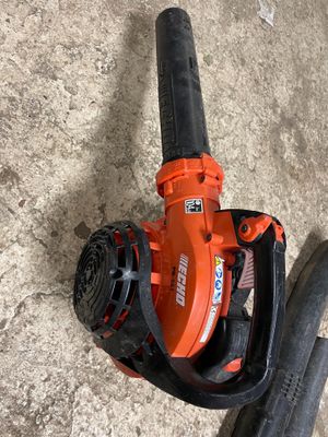 une soufflerie orange et noire posée par terre à côté d'un tuyau d'arrosage
