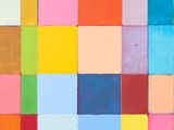 Des blocs aux couleurs vives sont disposés en carré sur un mur