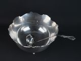 a silver bowl with a spoon in it on a black background