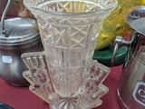 un vase en verre posé sur une table, à côté d'autres objets en verre