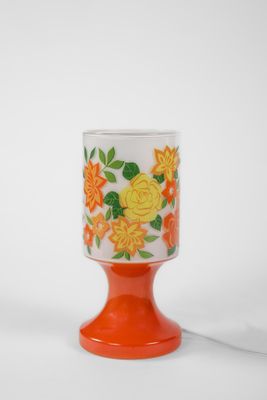 un gros plan d'une tasse orange et blanche ornée de fleurs