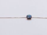 a gold chain bracelet with a blue bead on it