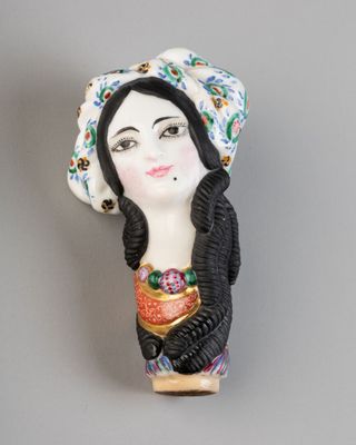 une image représentant une figurine de femme portant un chapeau sur la tête