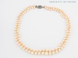 a close up of a necklace with pearls on a white surface