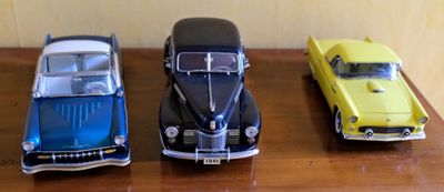 Quatre petites voitures sont alignées sur une table en bois