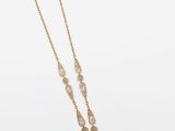 un collier en or composé d'une longue chaîne à laquelle est suspendu un pendentif en forme de larme